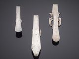 three pieces of silverware on a black surface with a black background