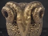 a gold statue of a ram on a marble surface