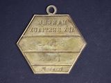 an antique brass medal with the name of a man on it
