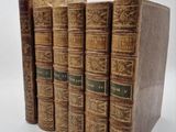 four old books sitting on top of each other on a white surface