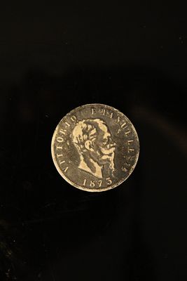 une pièce d'argent posée sur une surface noire, à côté d'un objet noir
