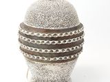a silver vase with a chain around it on a white surface