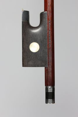 un gros plan d'un archet de violon sur fond gris