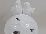 a white vase with two birds sitting on top of it