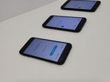 four cell phones are lined up on a white table