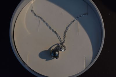 un collier en argent orné d'une perle noire sur une plaque blanche