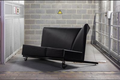 une chaise noire qui se trouve dans une pièce dont le mur est en briques