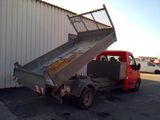 a red truck with a metal ramp in front of a building