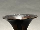 a black vase sitting on a table with a gray background