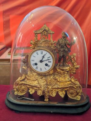 une horloge en or sous un dôme de verre sur une table