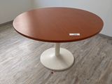 une table ronde avec un piètement blanc dans une pièce
