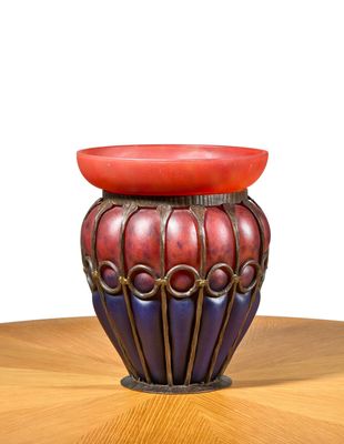 a red and blue vase sitting on a wooden table