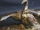 a bronze statue of a duck on a log