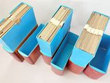 three blue boxes filled with stacks of wooden sticks sitting on top of a white surface