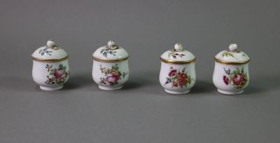 three small porcelain jars with floral designs on them on a gray surface