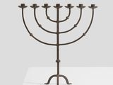 a metal menorah on a white pedestal with a gray background