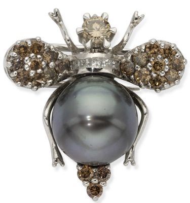 a close up of a black pearl and diamond bee broochle