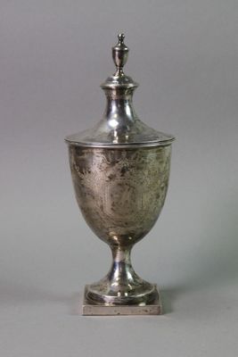 an antique silver cup with a lid on a metal stand