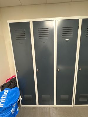 three lockers in a room with a blue bag on the floor