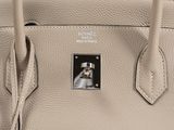 a close up of a beige leather handbag on a white surface