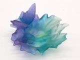 une fleur bleue et violette posée sur une surface blanche
