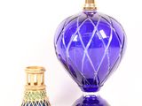 a blue glass vase next to a gold candle holder