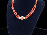 un collier composé de perles de corail, présenté sur un mannequin