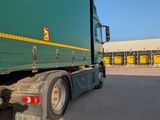 a green semi truck parked in front of a building