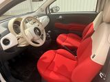 the interior of a small white car with red seats and a steering wheel