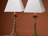 two lamps on a dresser in a room with a brown wall