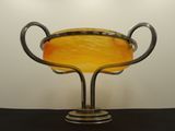 a yellow glass bowl on a metal stand on a table