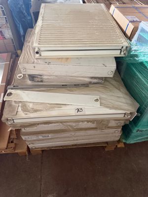 Des cartons contenant des climatiseurs sont empilés sur une palette dans un entrepôt