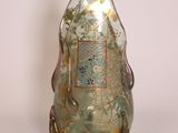 a green glass bottle with a gold decoration on it