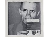 black and white photograph of a man holding a camera in front of his face