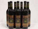 six bottles of wine are lined up on a white surface