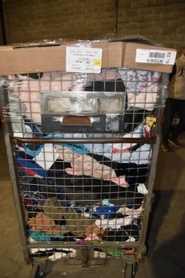 a cart full of clothes that is sitting in a warehouse