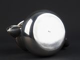 a close up of a silver tea pot on a black surface