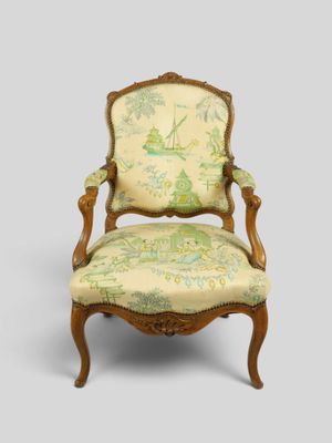 une vieille chaise dont le dossier est recouvert de tissu vert et blanc