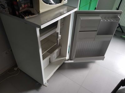 a small refrigerator with a microwave on top of it