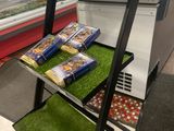 une vitrine dans une épicerie dont les étagères sont recouvertes d'herbe