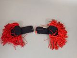 pair of black and red hair clips with red fringes on a white surface