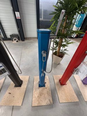 une pompe à main bleue et rouge posée sur un plancher en bois