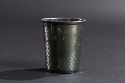 un gros plan d'une tasse en métal posée sur une surface noire