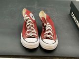 pair of red converses on a black surface with a box