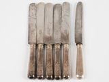 six knives are lined up in a row on a white surface