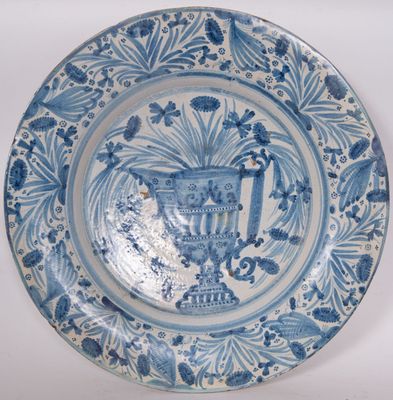 une assiette bleue et blanche sur laquelle est représenté un vase