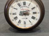 a small clock with roman numerals sitting on a table