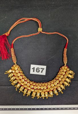 un gros plan sur un collier en or orné d'un pompon rouge