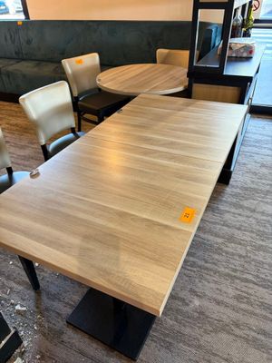 une longue table avec des chaises et un banc dans un coin