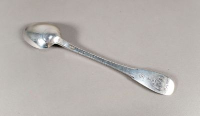 une cuillère en argent avec un manche de cuillère sur une table